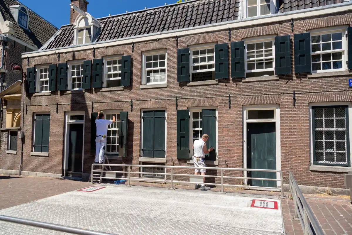 Schilder werkt met een kwast aan een houten kozijn